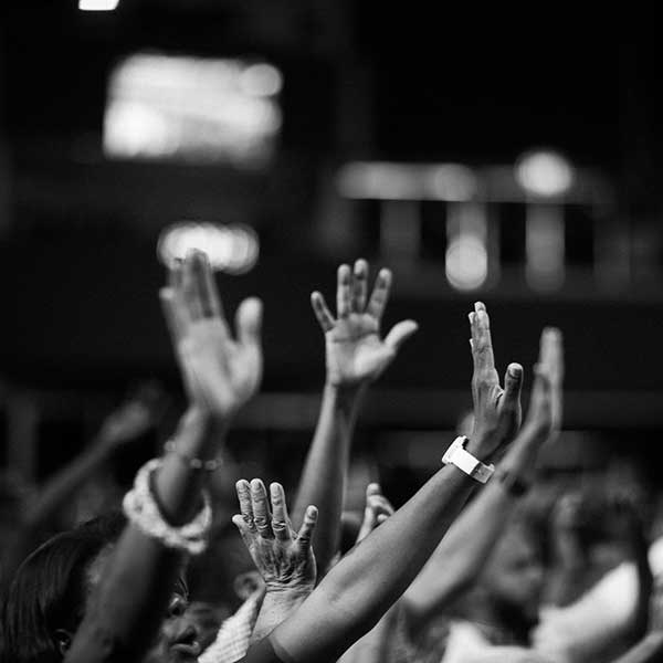 A black and white room full of people with their hands up waiting to ask a question